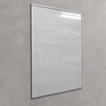 A large, empty white poster or display board with a slim silver frame, mounted on a textured gray concrete wall. The glossy surface reflects a ceiling light and faint watermarks.