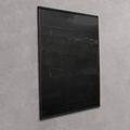 A large, black-framed wall art print or poster hanging on a textured light gray wall. The artwork itself is predominantly black with subtle, low-contrast dark gray and white abstract patterns.