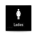 A square black sign with a white female restroom symbol, the word 'Ladies,' and small Braille text near the lower left, shown on a light gray background.